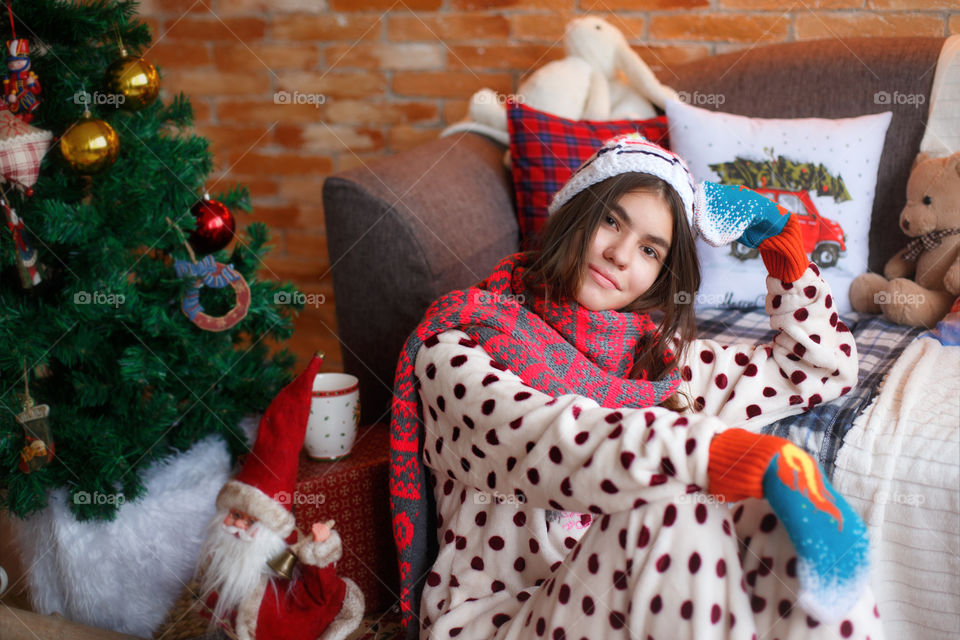 Teenage girl leaning on sofa near christmas tree