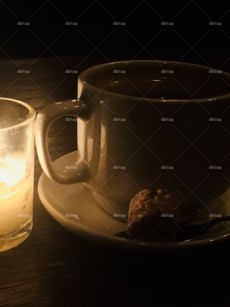 Coffee at a restaurant on a wooden table next to candle light 