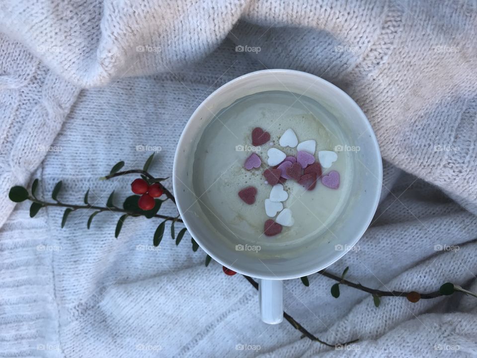 White cup of white-hot chocolate with little sugary hearts on the top.