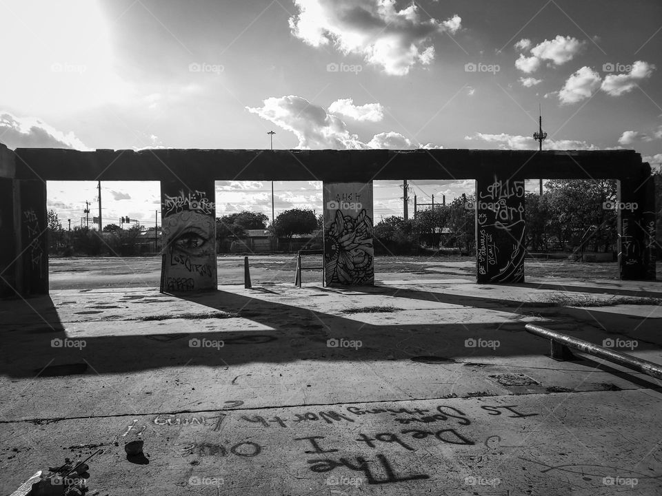 Shadows in black and white at sunset at an abandoned outdoor urban art facility. The debt I owe is something worth living 4 graffiti painted on floor.