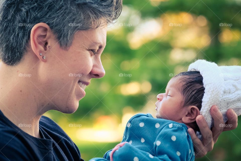 Mother holding newborn baby with look of happiness, happiness as an emotion in every day life, baby and mother are happy, happy and content expressions on faces, mother’s love brings happiness, mother is happy with newborn baby, mother and daughter 