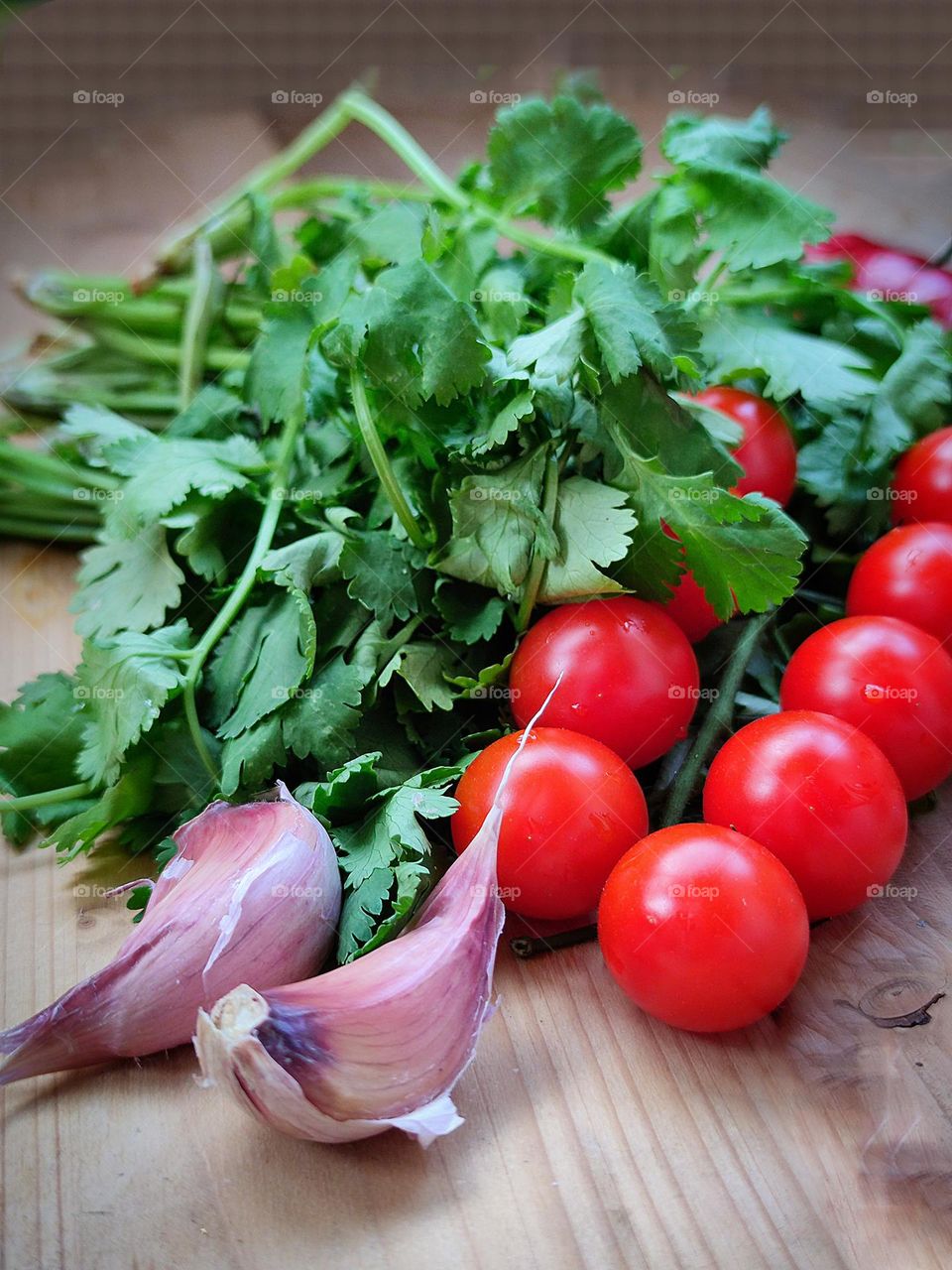 Vegetables. Red cherry tomatoes, two cloves of garlic and a bunch of green cilantro