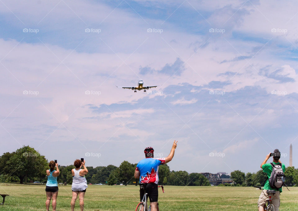 A crowd of people using their mobile devices to take photographs of a plane landing at National Airport in Washington DC