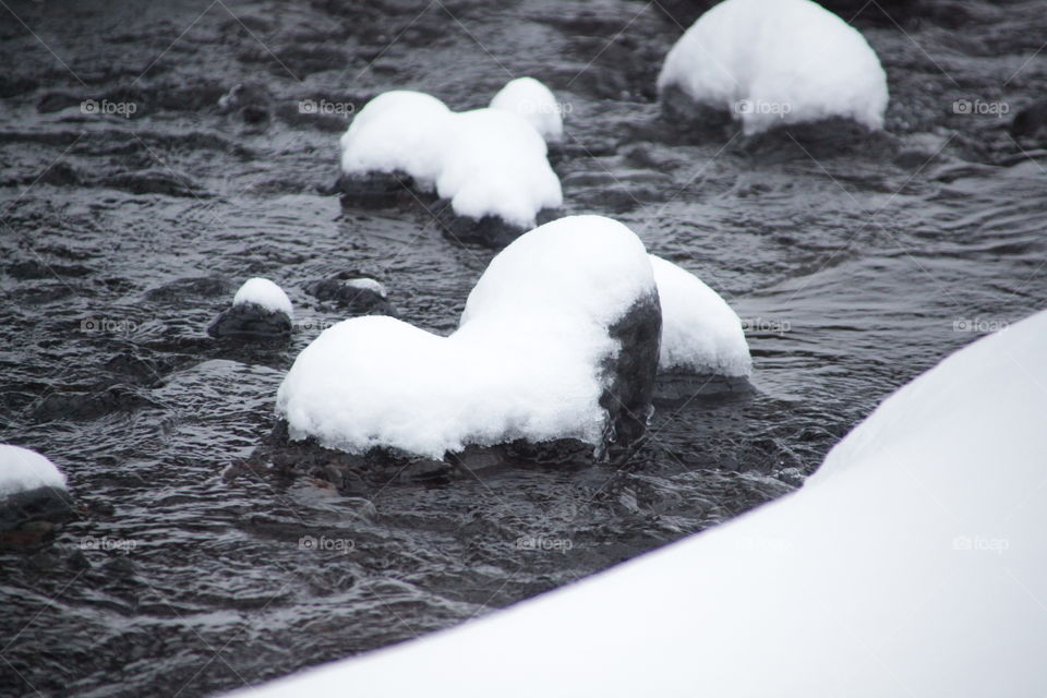 Beautiful heart shaped stone moulded by the river covered with snow 