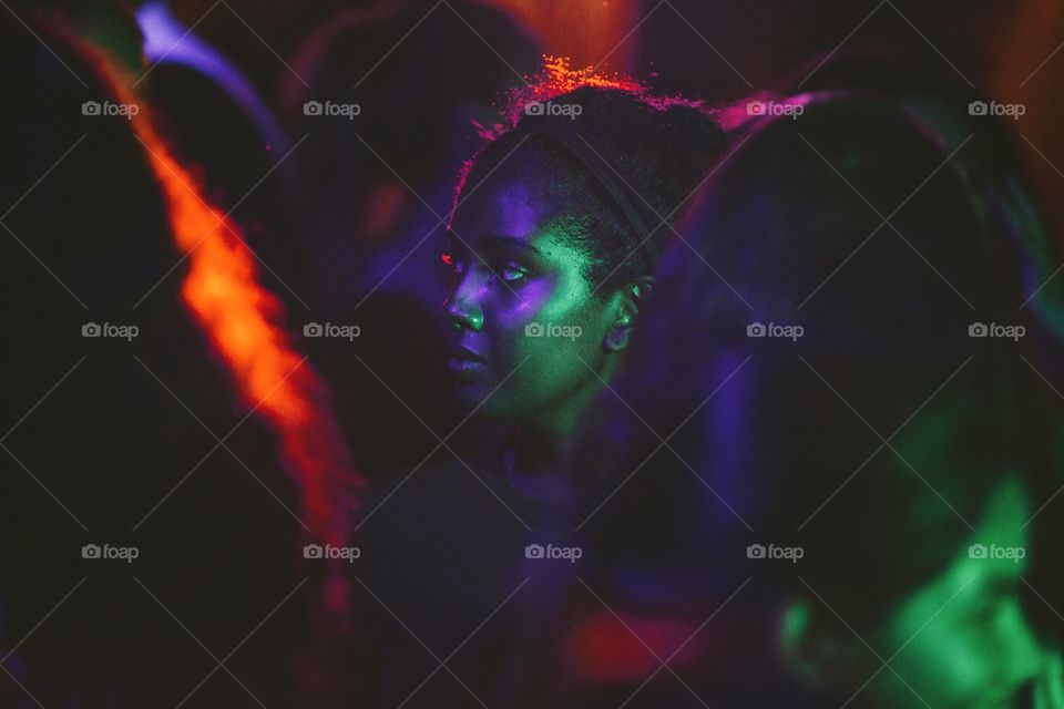 Young woman in a crowded room under colourful lighting
