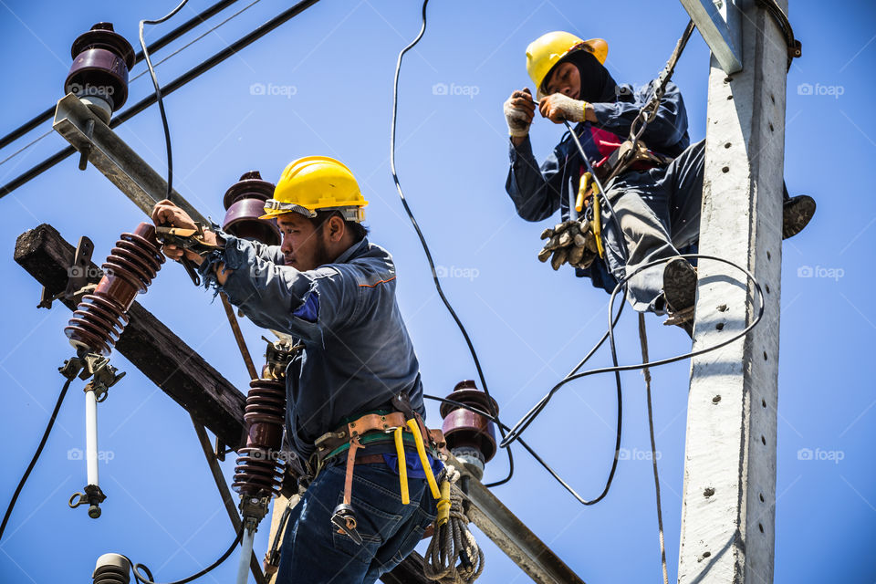 Electrician working together on the electricity pole to replace the electrical insulator