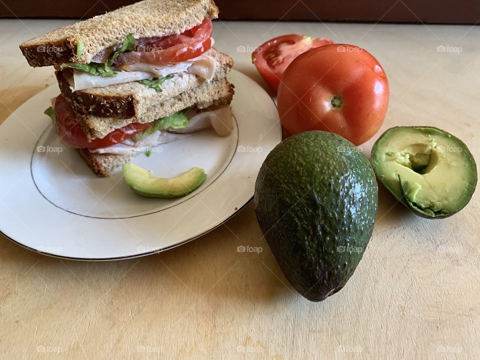 Healthy sandwiches made on whole wheat bread with sliced tomatoes, avocado and turkey.  