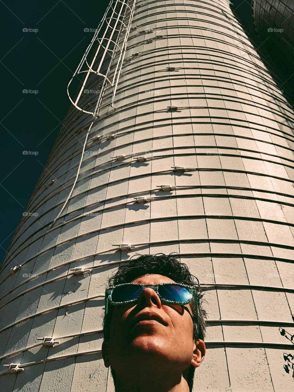 Woman looking up towards sun, basking in the sun, searching for a higher power, using the light, the power of light, woman wearing sunglasses in the sunshine, summertime shades, silo and woman, model by silo, deeper meaning 