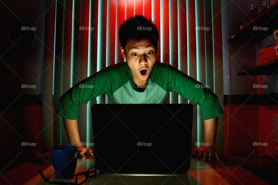 teenager acting surprised in front of a laptop computer