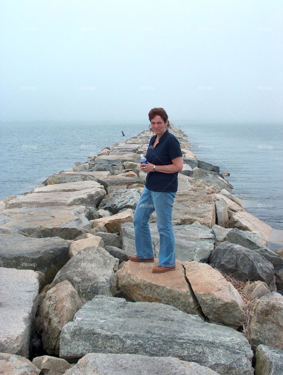 Woman standing on rocks in ocean 