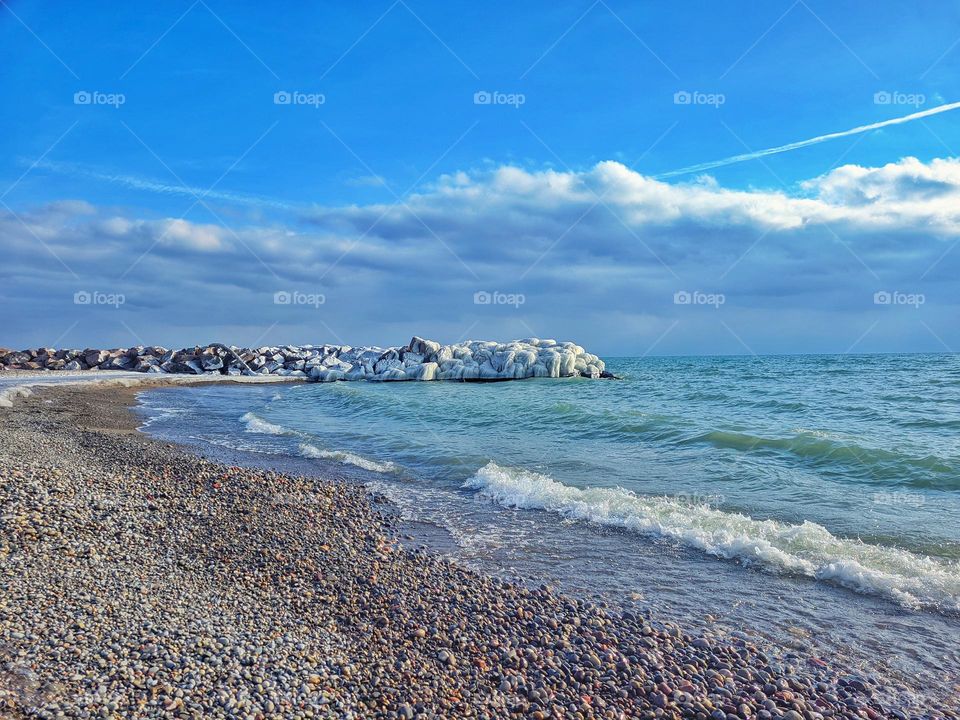 Scenic view of the snow covered rocks at the beautiful beach near Ontario lake,  Toronto. Blue sky. Winter landscape