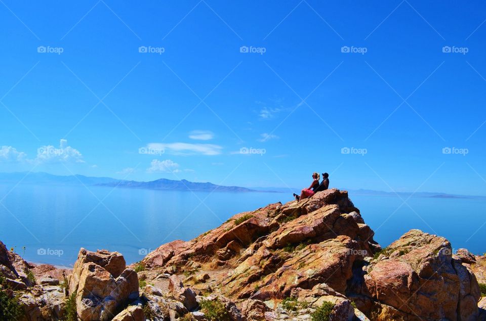 Couple sitting on rocky mountain at sea side