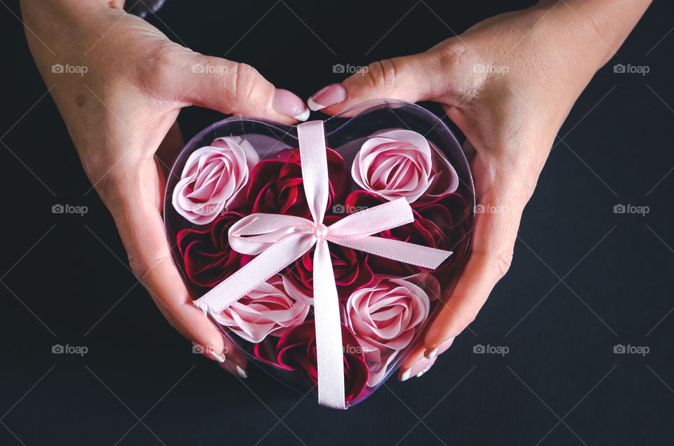Hands holding heart shaped box with roses