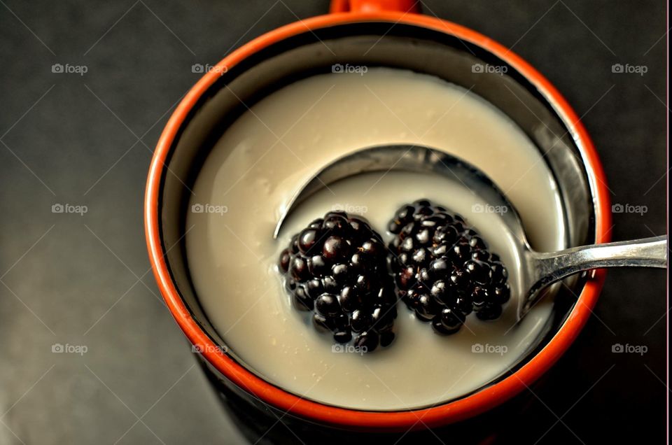 A pair of black raspberries swimming in condensed milk 