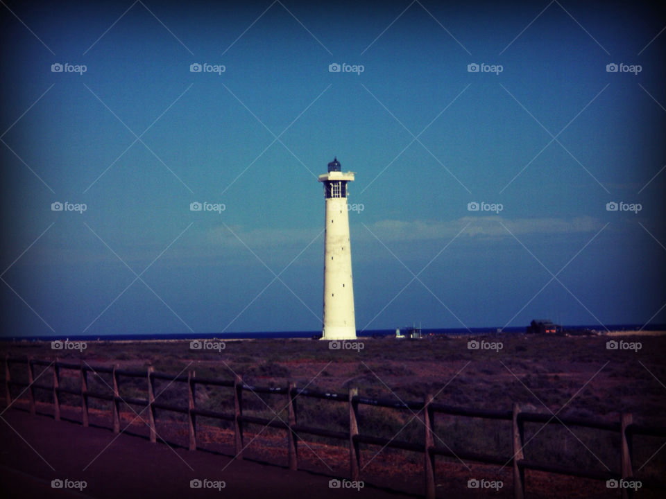 white lighthouse blue sky morro jable by vazisi