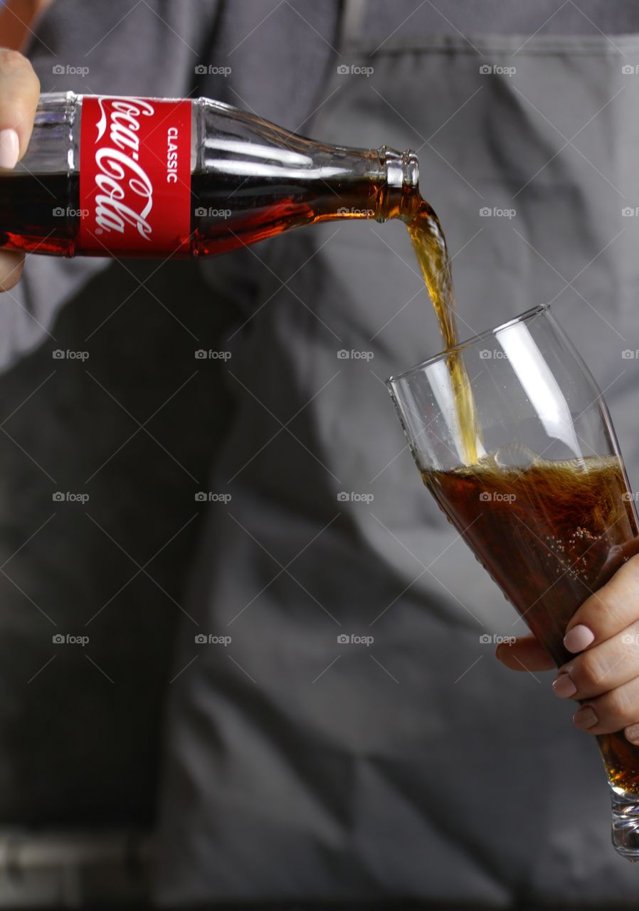 Female hands with a bottle of coca cola and glass 