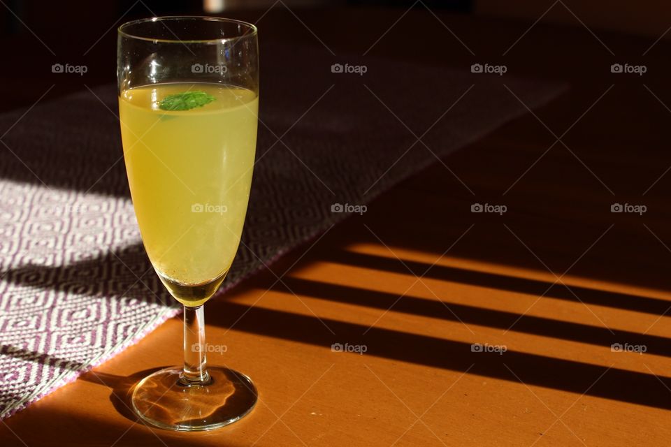 Yellow drink on a wooden surface, shadow and light