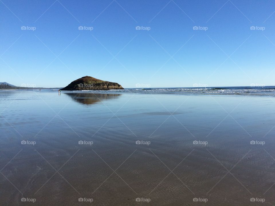 Reflection of rock in wet sand at beach