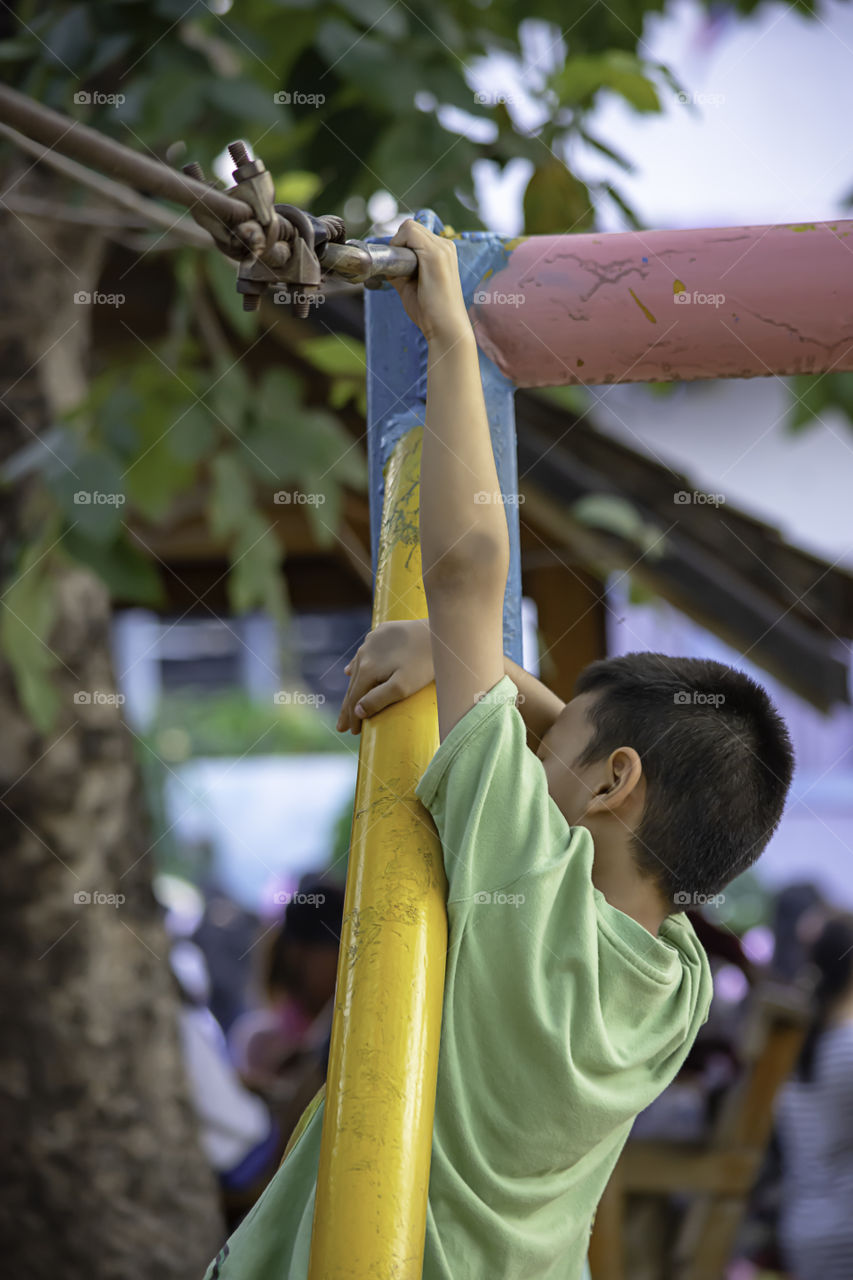 Asean boy nodes the wire rope In the playground.