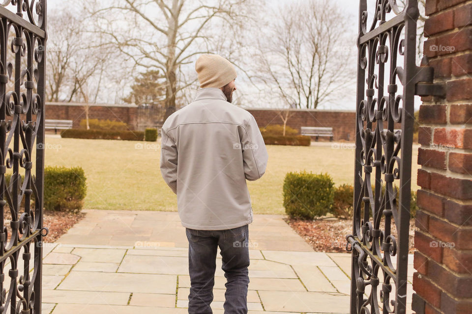 Man walking in park through the gate looking to the right 
