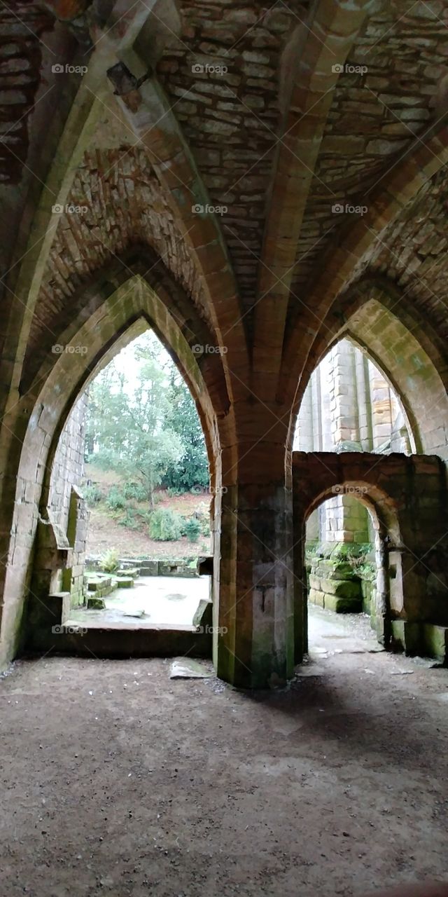 looking through gothic arches of ruins of ancient monastery