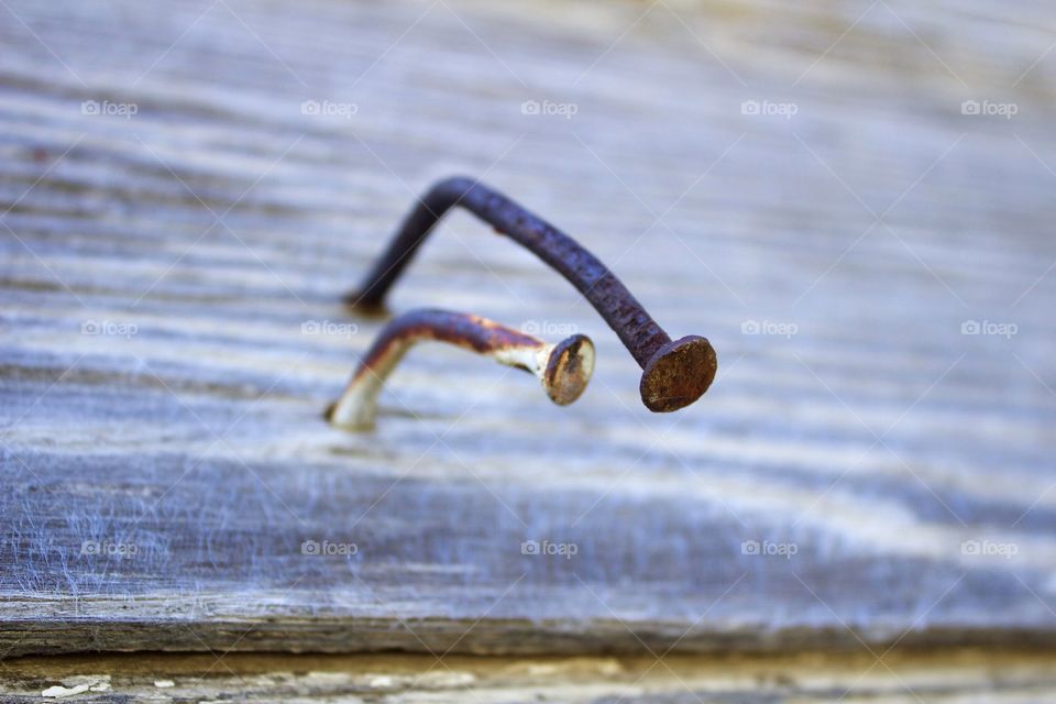 Closeup of two rusty, bent nails in weathered wood