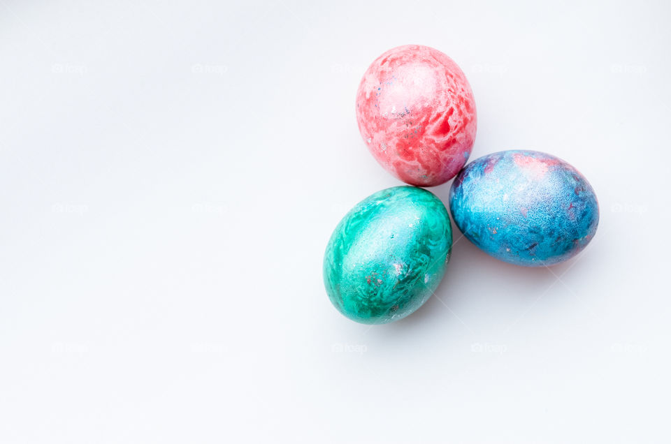 Top view of three colourful dyed Easter eggs on a white background.