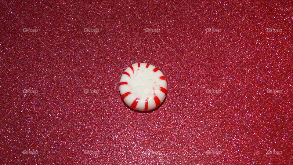 Peppermint candy on red glitter background 