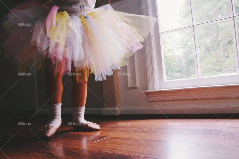 Low section of girl standing on hardwood floor