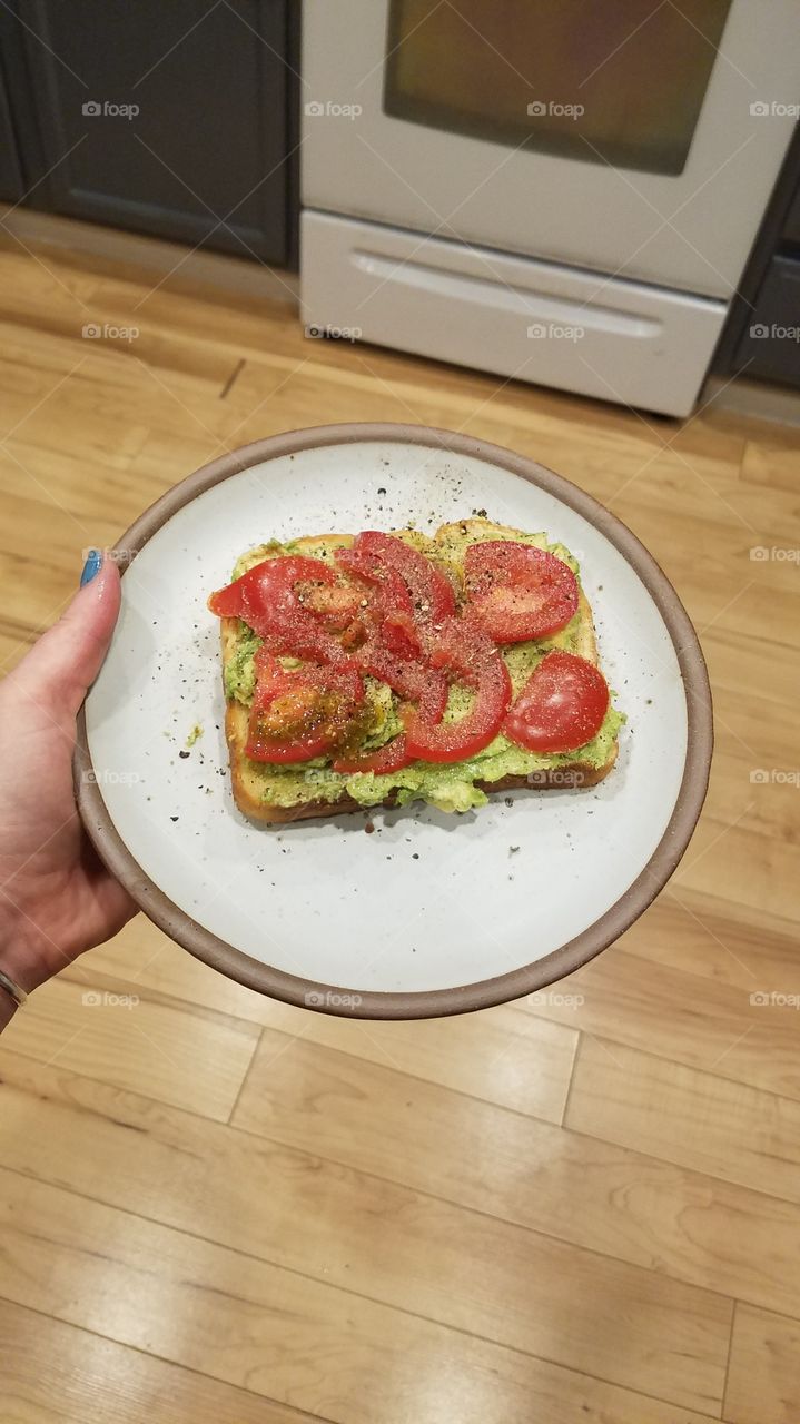 avocado toast with tomato on pottery plate