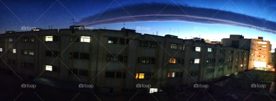 A nice panoramic evening in which a special wide cloud welcomes the night to the houses. 
It doesn't matter where the home is in this vast world , the important thing is that its residents give each other love and peace with their inside light