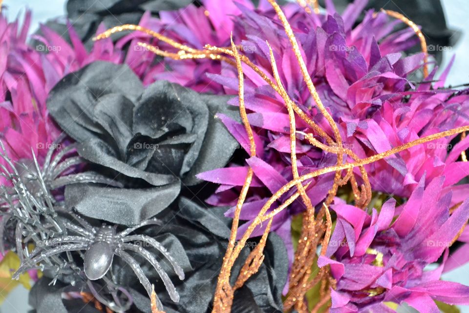 Close up of black and purple flowers mixed with orange sparkly branches 