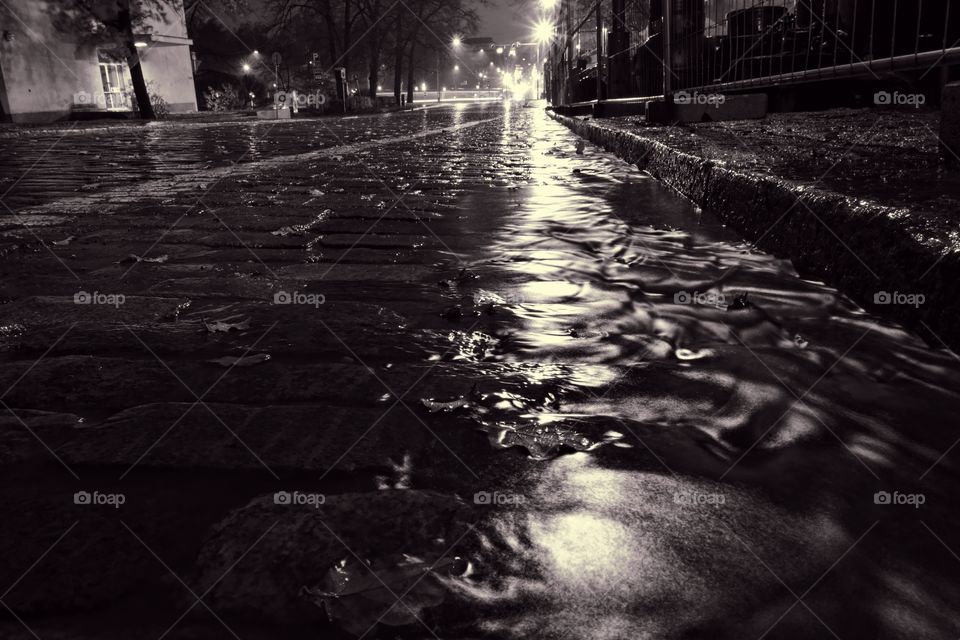 Rain water flowing down a street in down town Helsinki during a nightly autumn storm and creating miniature surge on a cobble street at Unioninkatu in Kaisaniemi district.