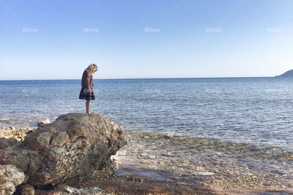 Cute girl standing on rock at coastline