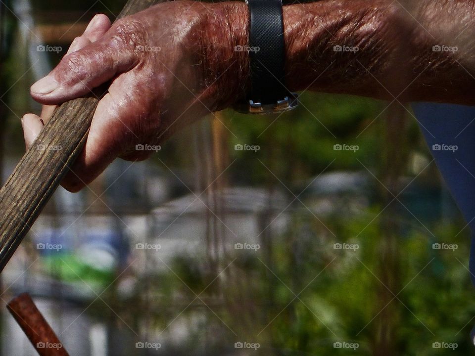 Old hands holding shovel parallel