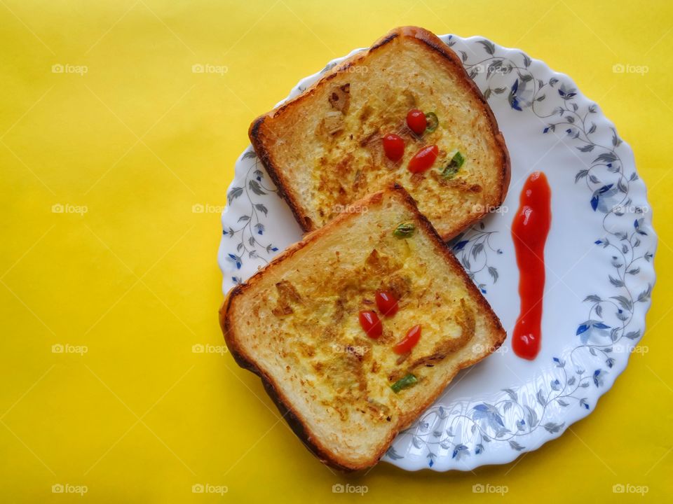 Bread egg omlet with ketchup in white plate on yellow background