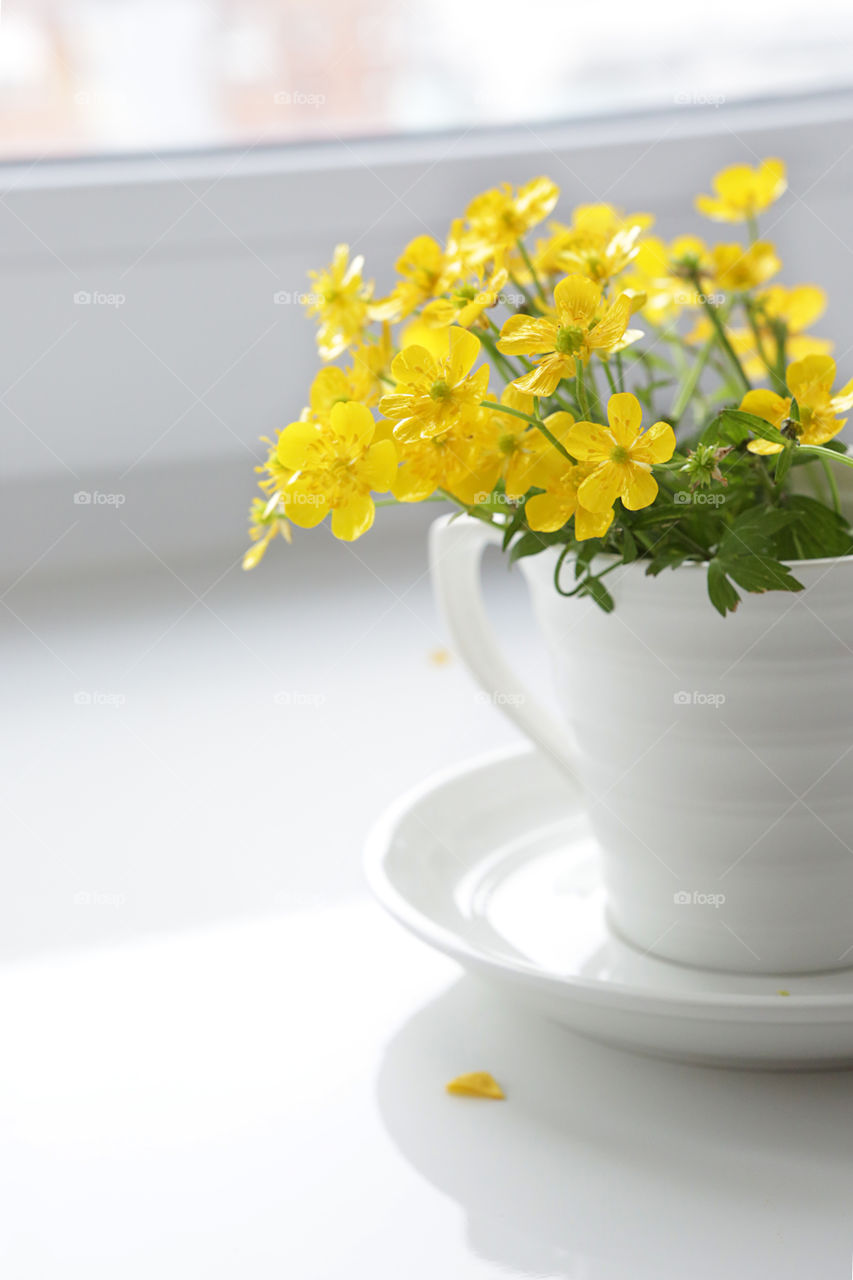 Cup of coffee with yellow flowers (ranunculus arvensis). Good morning!