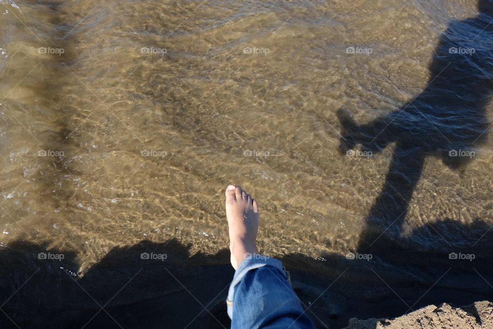 Foot stepping into river water, checking water temperature