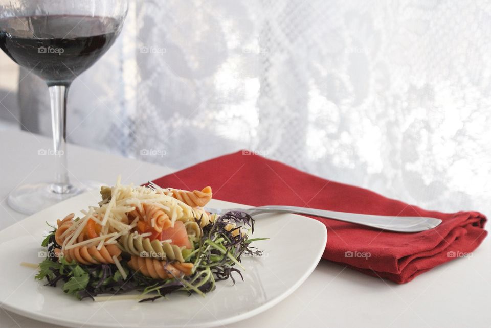 Pasta salad on table with wineglass