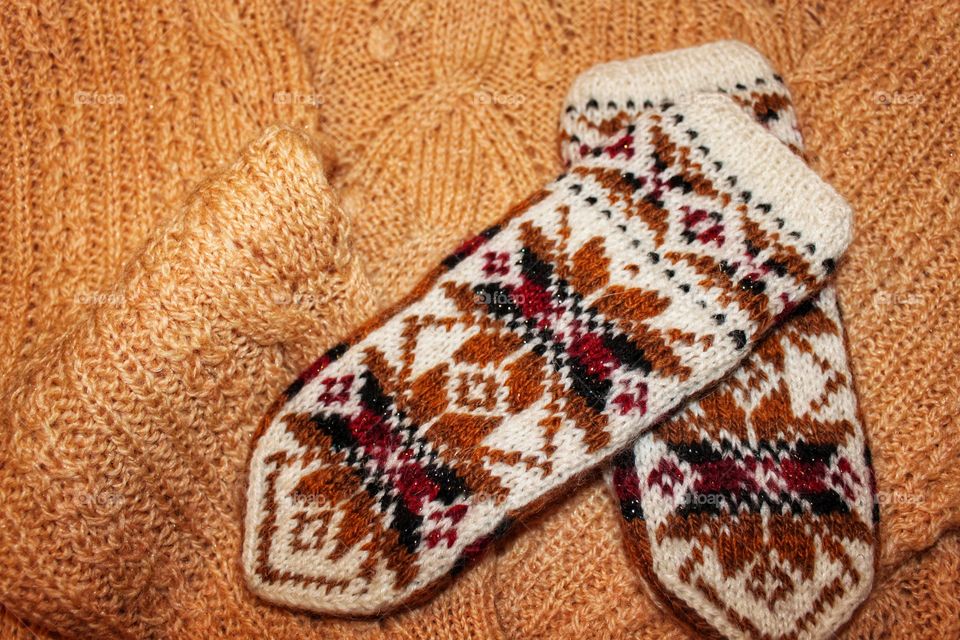 knitted wool warm sweater and white mittens with a pattern. Warm winter clothing.