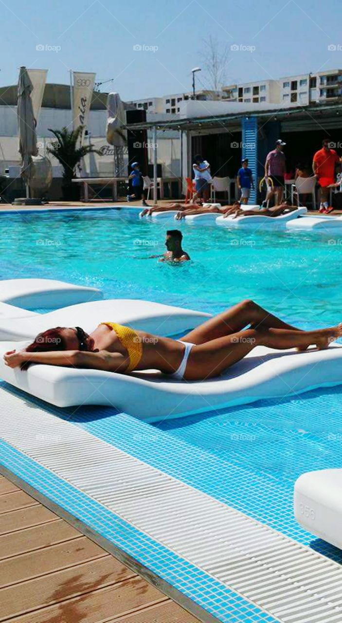Woman in bikini lying on airbed at swimming pool