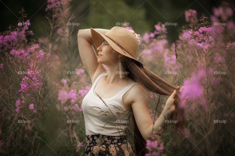 Beautiful young woman in a field of blossom flowers in boho style