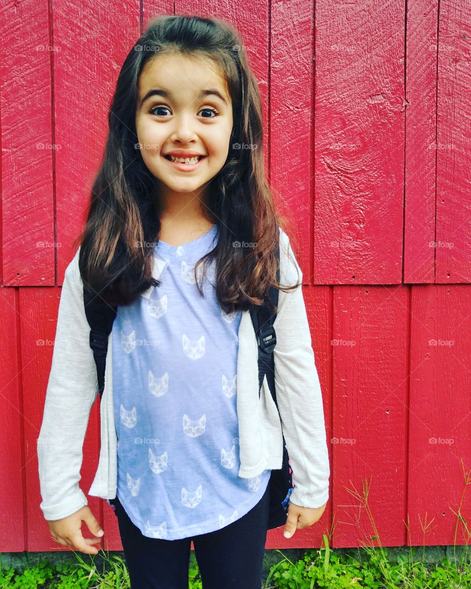 Cute girl standing against wooden wall