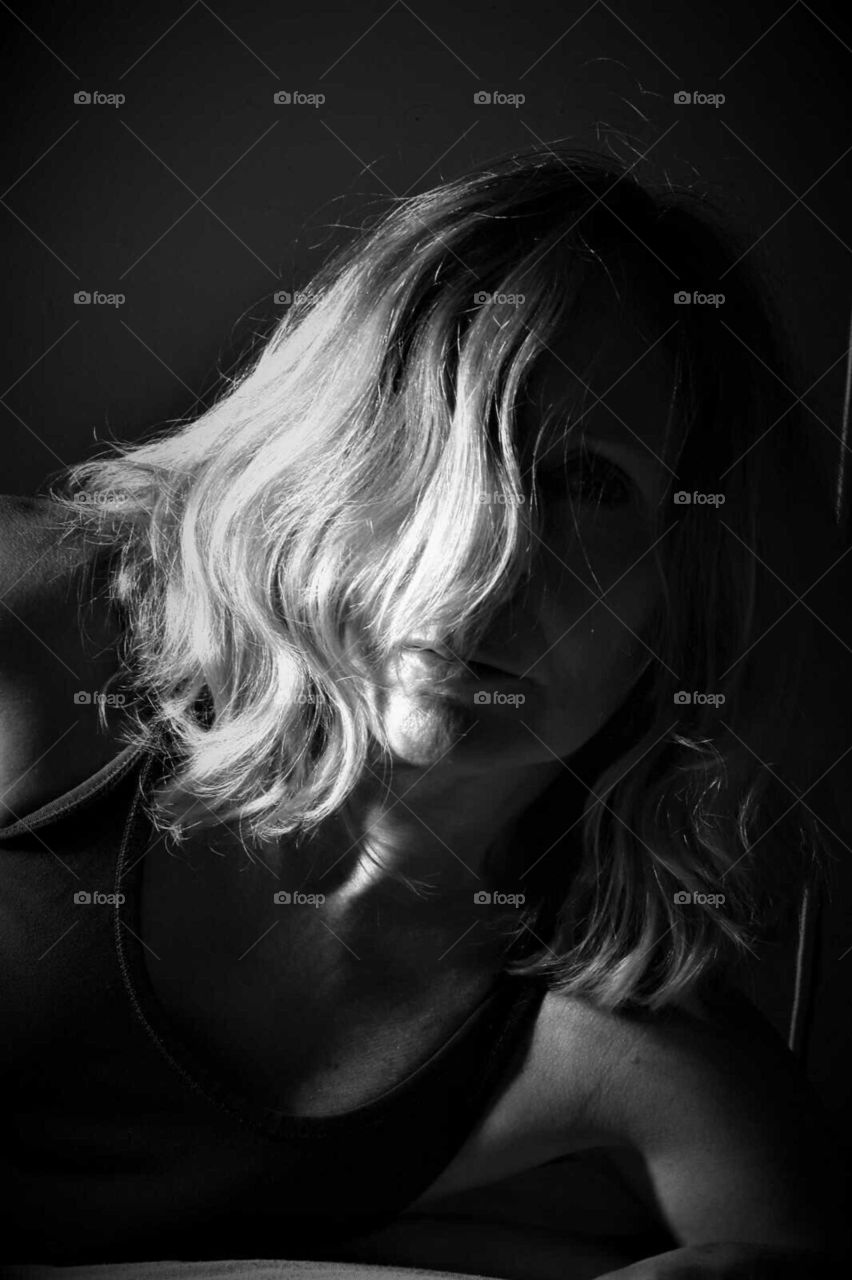 low key black and white portrait with woman showing her blond curly hair lock