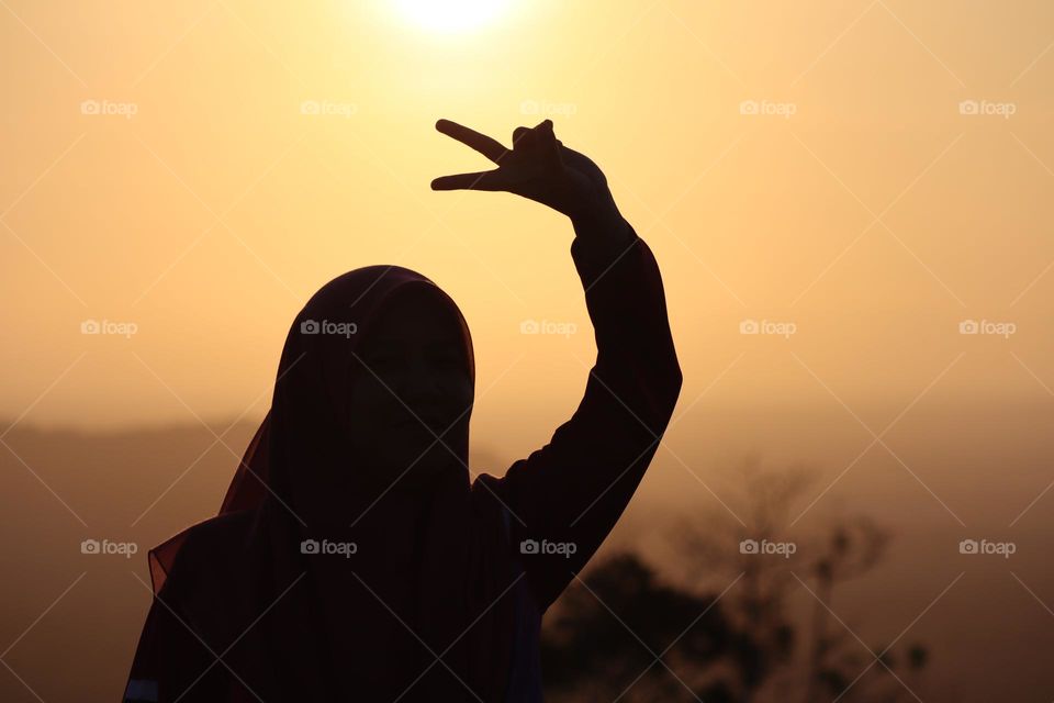 A silhouette of a girl showing a peace hand sign