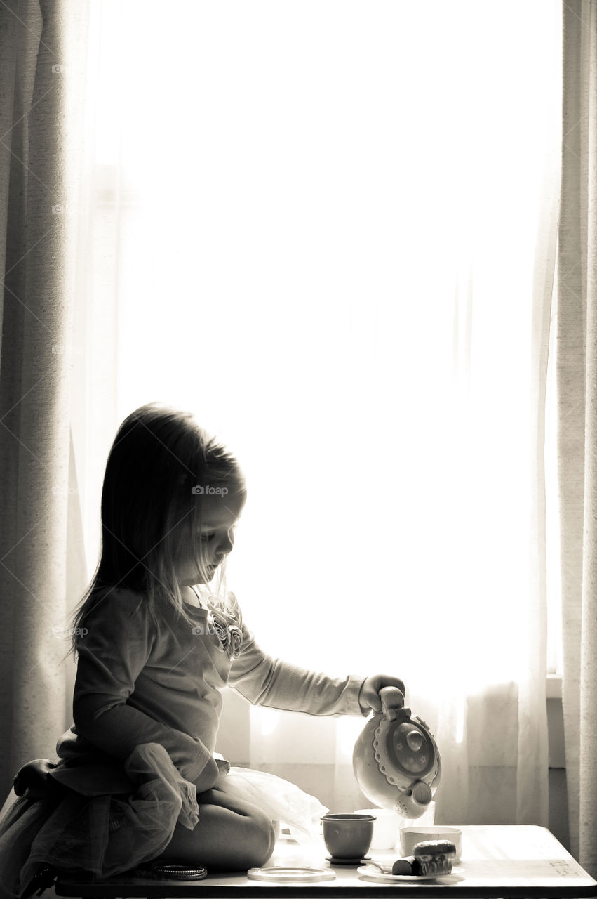 Tea for One . A 3 year old girl pretends to pour tea, as she does every morning. 