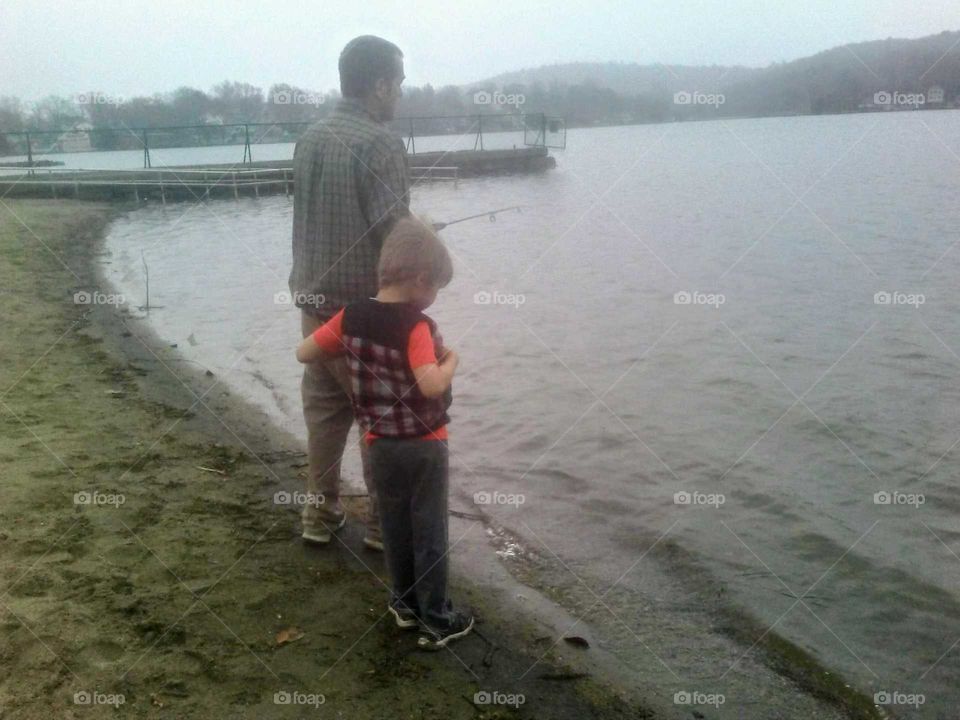 My youngest son is patiently waiting to get the fishing pole back from his father during one of their fishing trips together. It had rained earlier helping add to the healthy, relaxing activity.