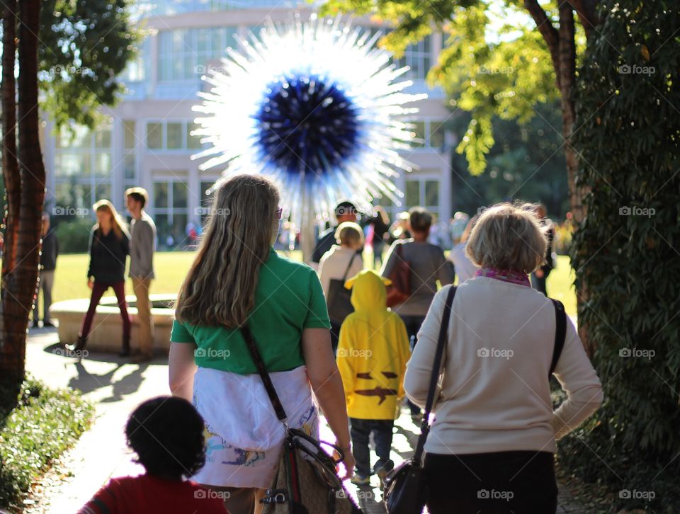 People enjoying weekend with friends and family while spending time at urban park. This park is Atlanta botanical garden and currently displays Chihuly glass art. 