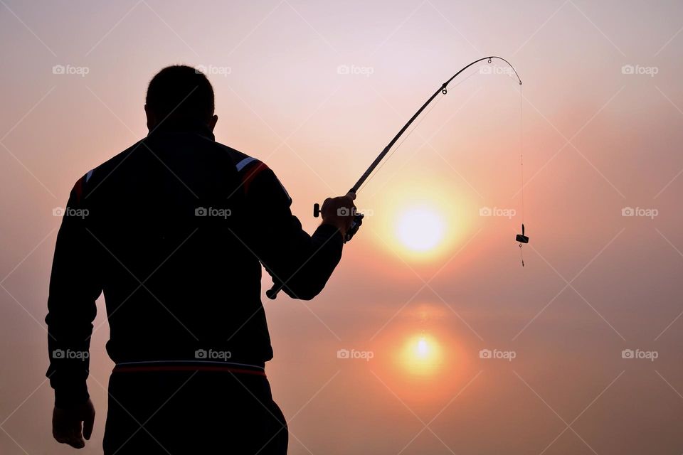 Man fishing on sunrise. Alone with nature.