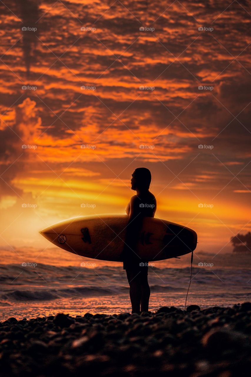 Silhouette of surfer in a magical sunset on the beach